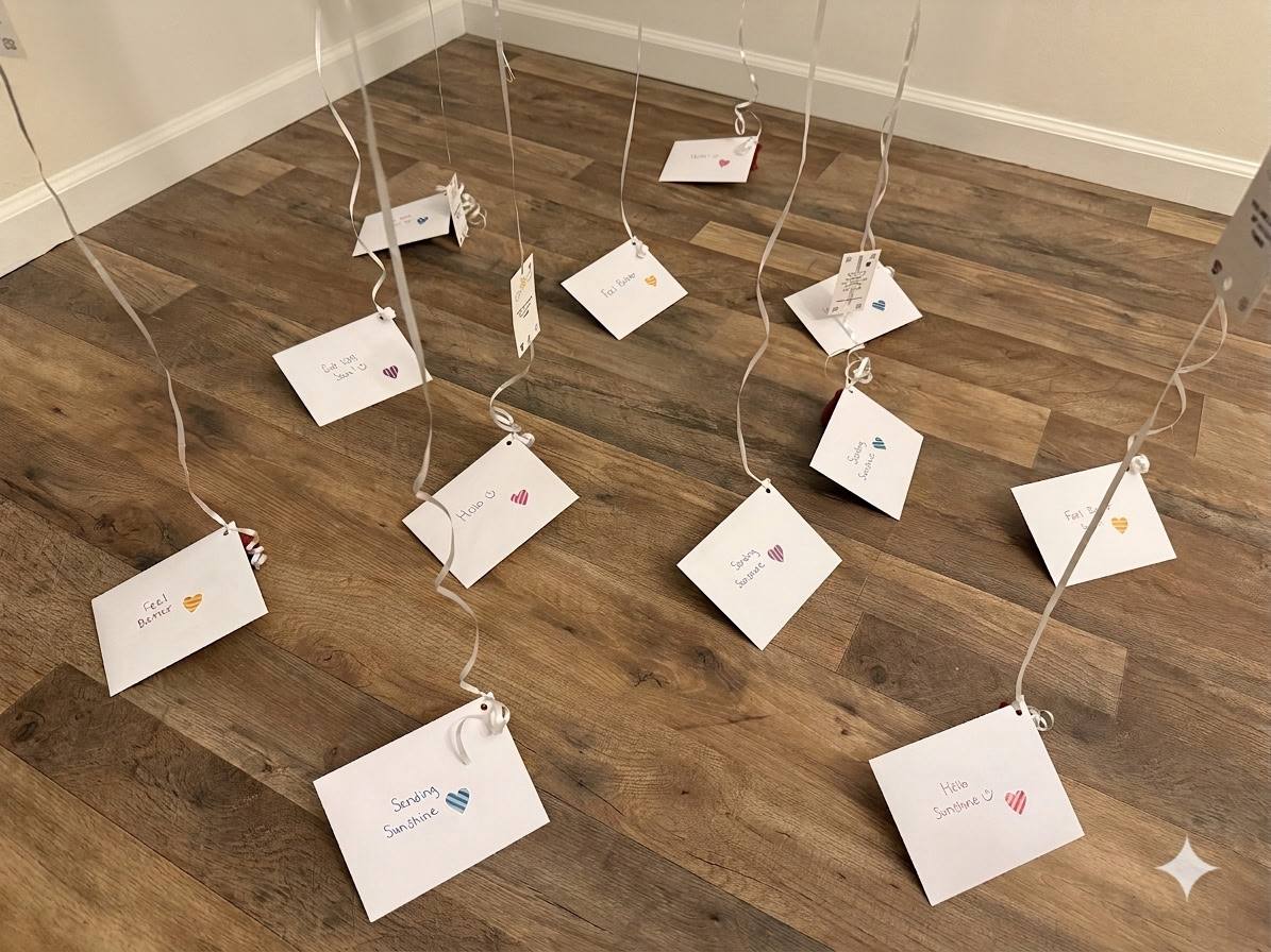 Hand-written card envelopes decorated with small hearts and messages like Sending Sunshine hang from balloon ribbons.